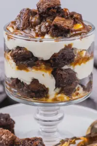 Delicious caramel brownie trifle served in a glass dish, showcasing layers of brownie, cheesecake pudding, and caramel sauce.