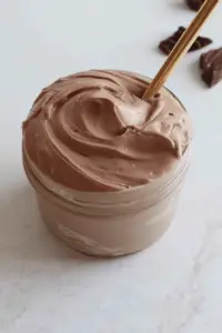 Chocolate Greek yogurt in a bowl topped with cocoa powder and honey, served with fresh fruits.