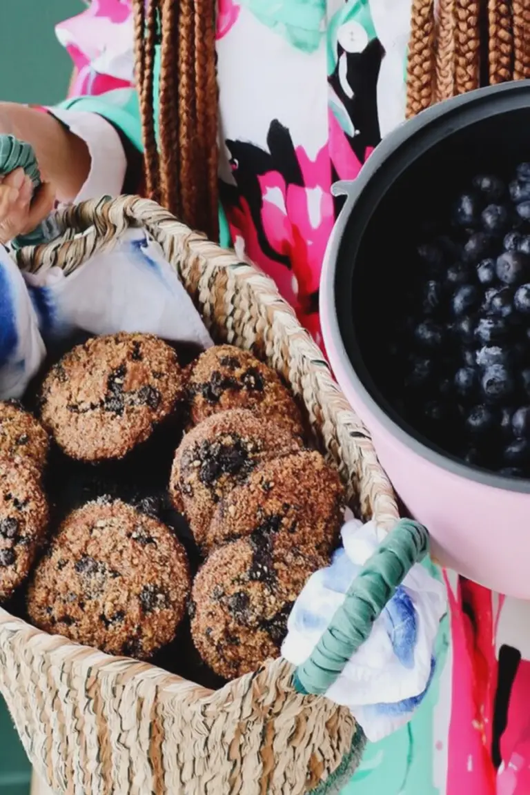 Close-up of Lani's blueberry power muffins with fresh blueberries and powdered sugar on a wooden table.