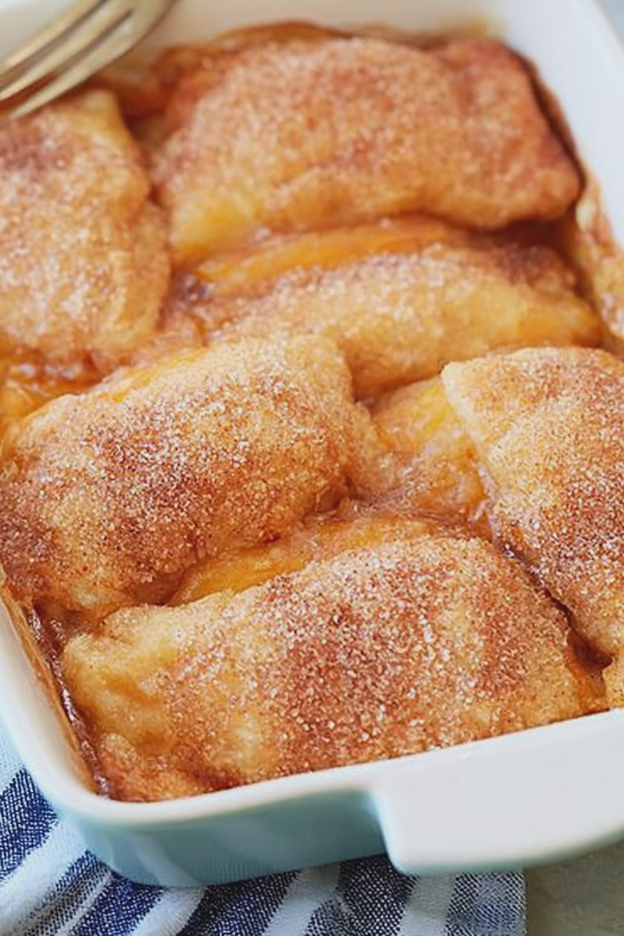 Delicious peach dumplings served warm with vanilla ice cream and cinnamon on a wooden table.