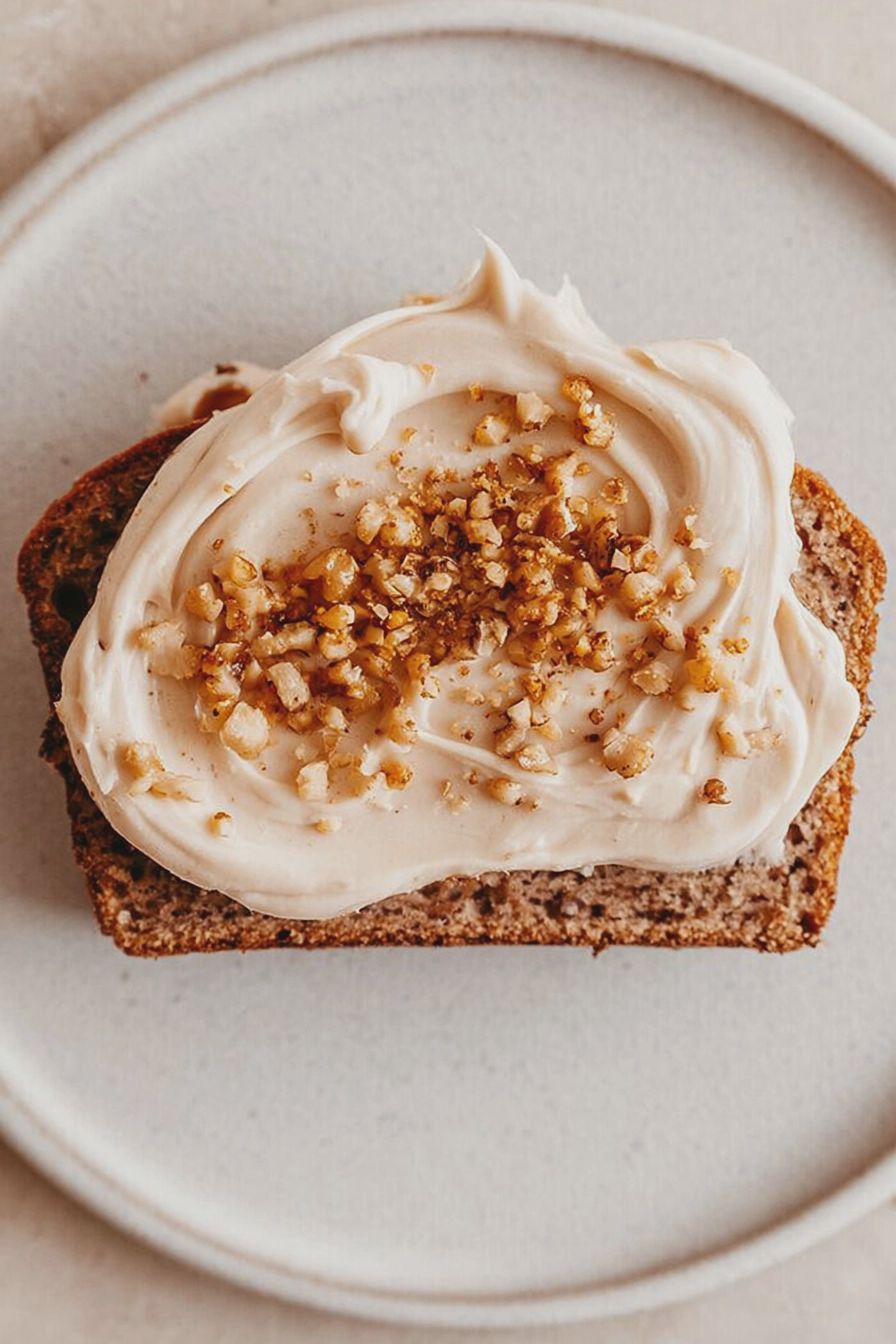 Sliced banana walnut bread with espresso mascarpone and honey on a wooden board, alongside a cup of espresso.
