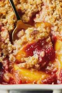 Delicious homemade strawberry peach crisp topped with whipped cream and fresh fruit.