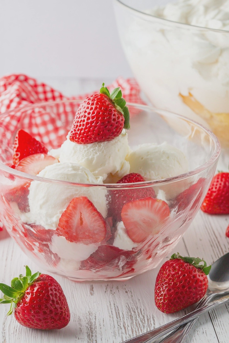 Strawberry punch bowl cake with layers of whipped cream and fresh strawberries in a glass punch bowl